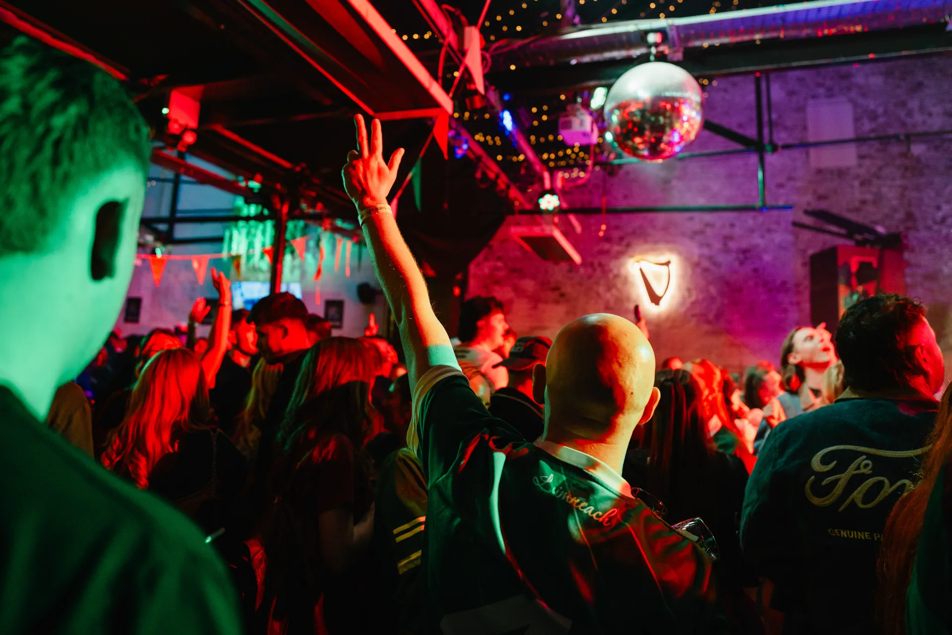 Packed late-night dancefloor under festive red and emerald stage lighting at Nortons Digbeth