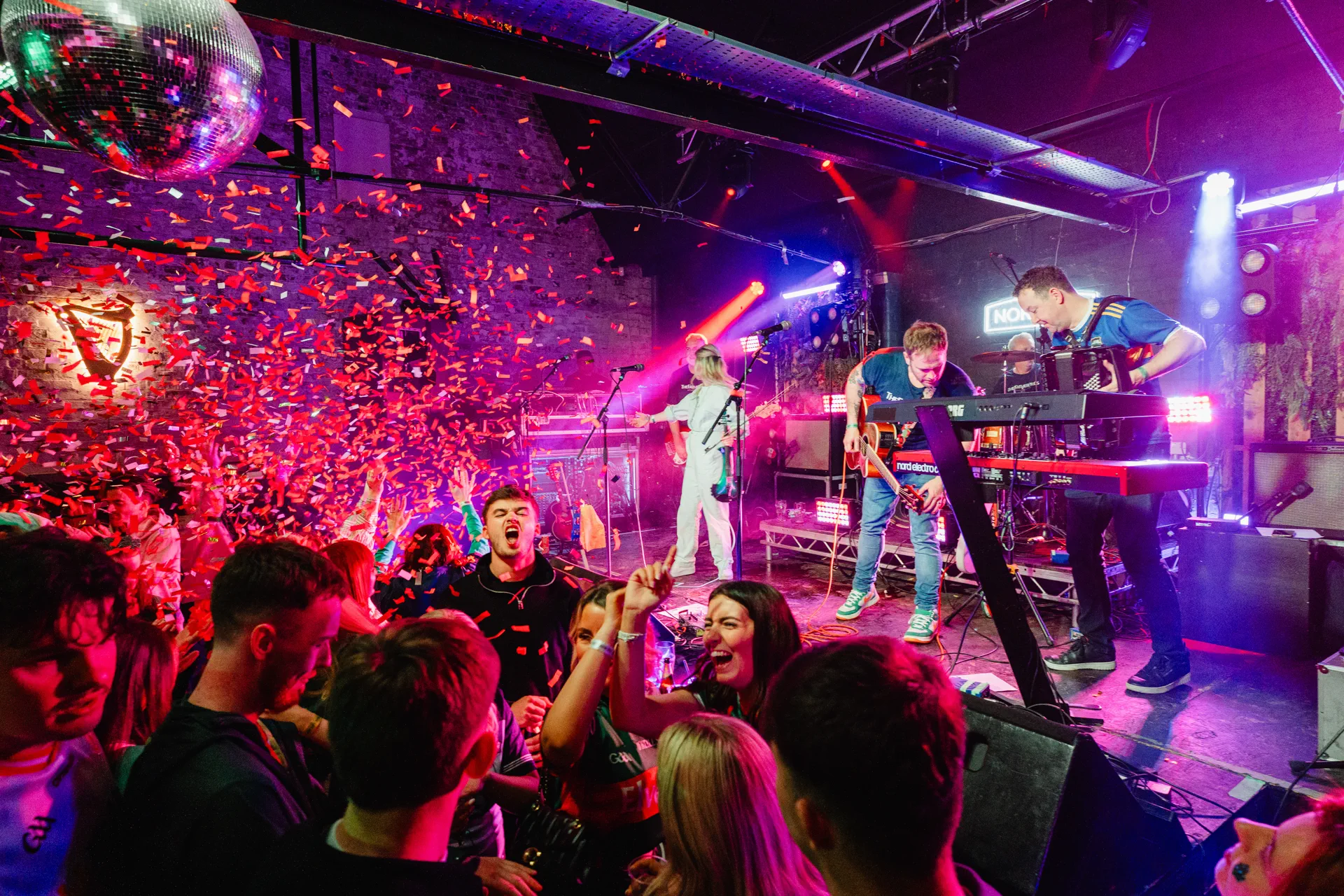 Live band on stage at Nortons Digbeth under confetti shower, disco ball and glowing Guinness harp