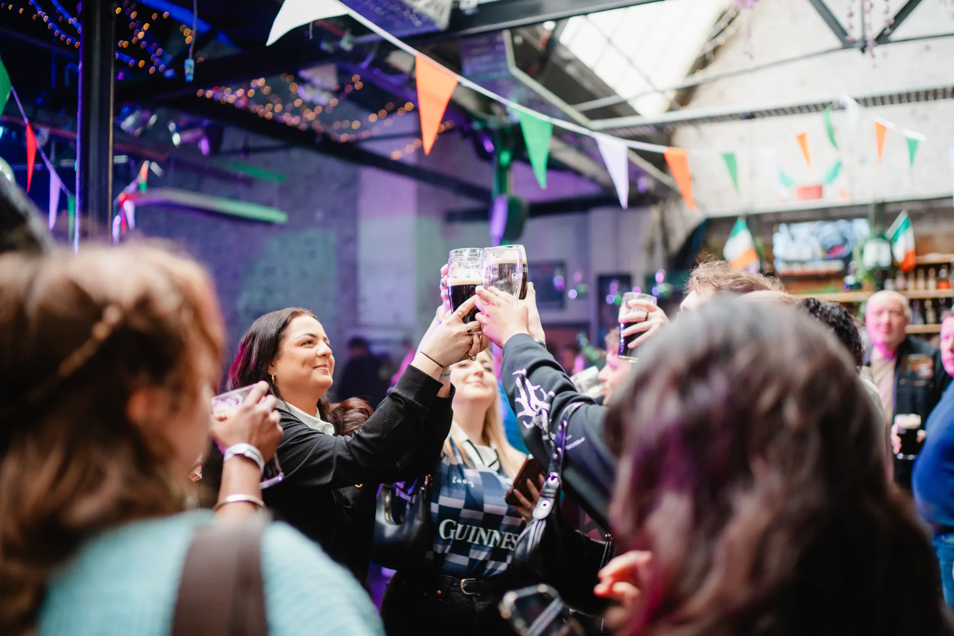 Friends raising creamy pints of Guinness in a celebratory Christmas toast at Nortons Digbeth