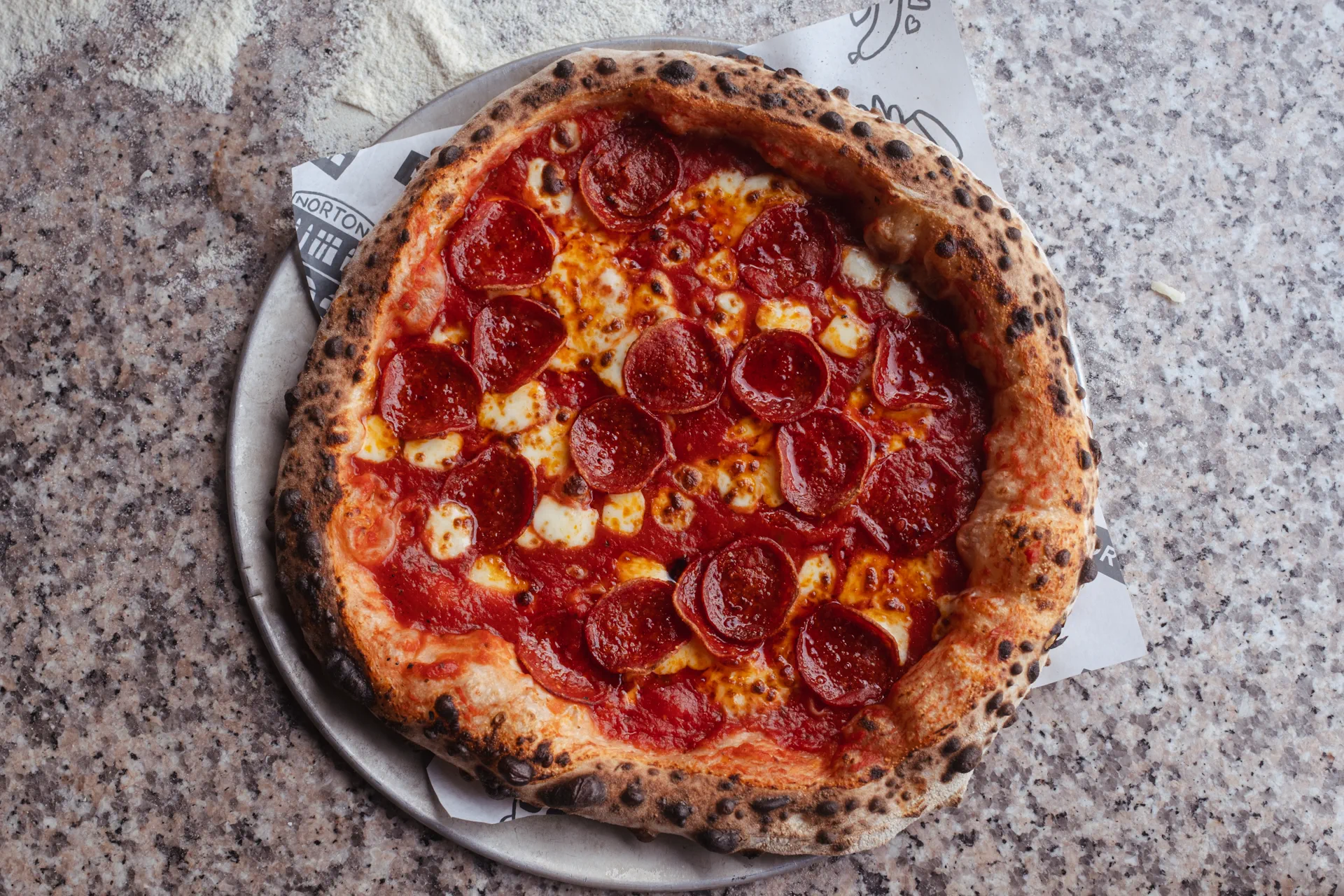Rustic freshly baked artisanal wood-fired sourdough pizza on wooden peel board in ambient Irish pub courtyard